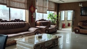 A spacious lobby with a large brown leather sofa, a glass coffee table, and a potted plant. - Ce Heng Hengjie Business Hotel (Ceheng)