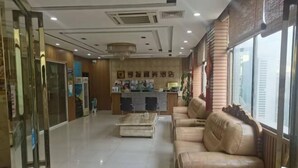 A hotel lobby with a reception desk, seating area, and a large window. - Ce Heng Hengjie Business Hotel (Ceheng)
