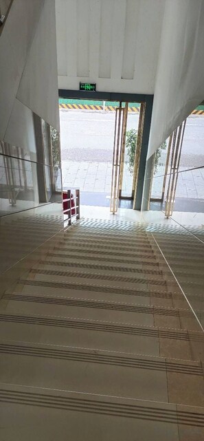 An interior corridor with a patterned floor, a door leading outside, and a sign above the door. - Ce Heng Hengjie Business Hotel (Ceheng)