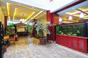 A lobby with a marble floor, a large fish tank, potted plants, and a seating area. - Hongcheng Hotel (Luoping)