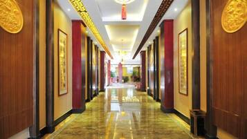 A hotel corridor with polished floors, wooden paneling, and framed artwork on the walls.