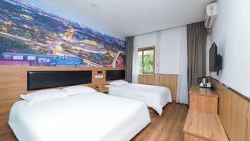 A hotel room with two beds, a large mural of a cityscape, a television, and a window with curtains.