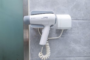 A hair dryer mounted on a wall with a coiled cord. - 99inn Selected (Beijing South Station Jiaomendong Metro Station) (Beijing)