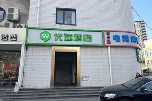 A building with a green sign indicating a 99 hotel and a red sign for an electric vehicle charging station. - 99inn Selected (Beijing South Station Jiaomendong Metro Station) (Beijing)
