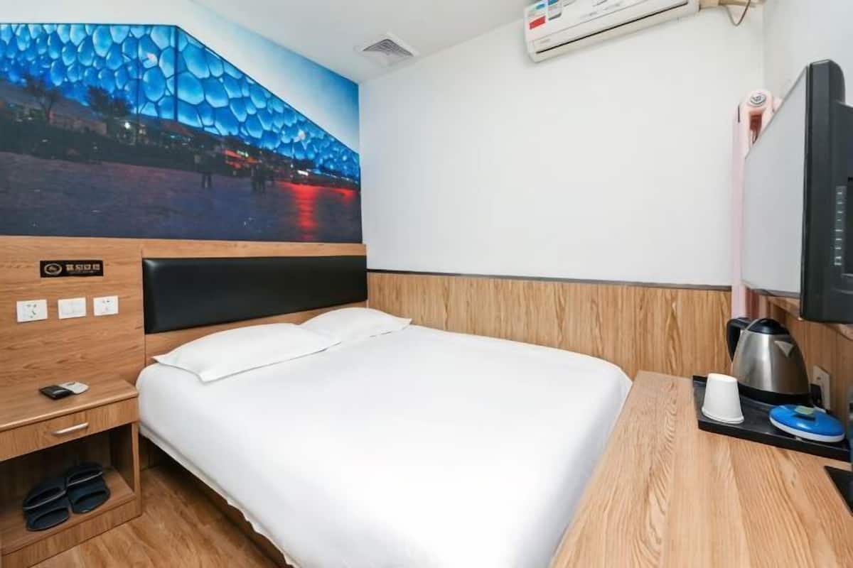 Habitación de hotel con una cama, un cuadro de un paisaje urbano, un televisor y una cafetera.
