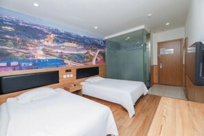A hotel room with two beds, a large cityscape mural on the wall, a wooden headboard, a desk, and a television. - 99inn Selected (Beijing South Station Jiaomendong Metro Station) (Beijing)