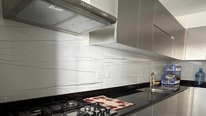 Una cucina moderna con elettrodomestici in acciaio inossidabile, un piano di lavoro nero e una parete attrezzata con un motivo originale.