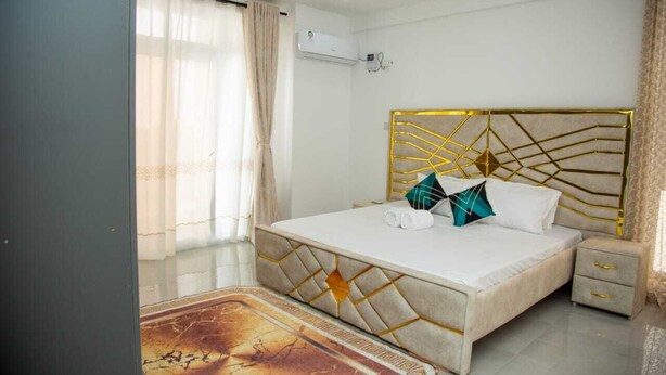 Una camera da letto moderna con un letto grande, un comodino e una testiera decorativa.