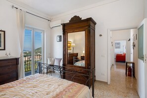 A bedroom with a bed, a dresser, a large mirror, and a balcony with a view. - Apartment 'Sguardo Sul Golfo' with Sea View, Wi-Fi and Air Conditioning (Massa Lubrense)