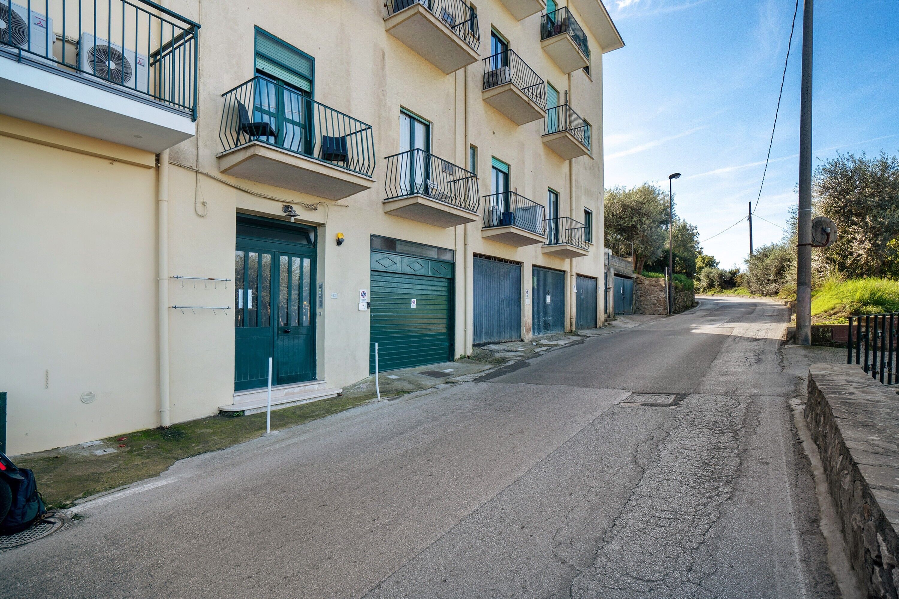 Una hilera de edificios residenciales con balcones y contraventanas verdes, bajo un cielo despejado.