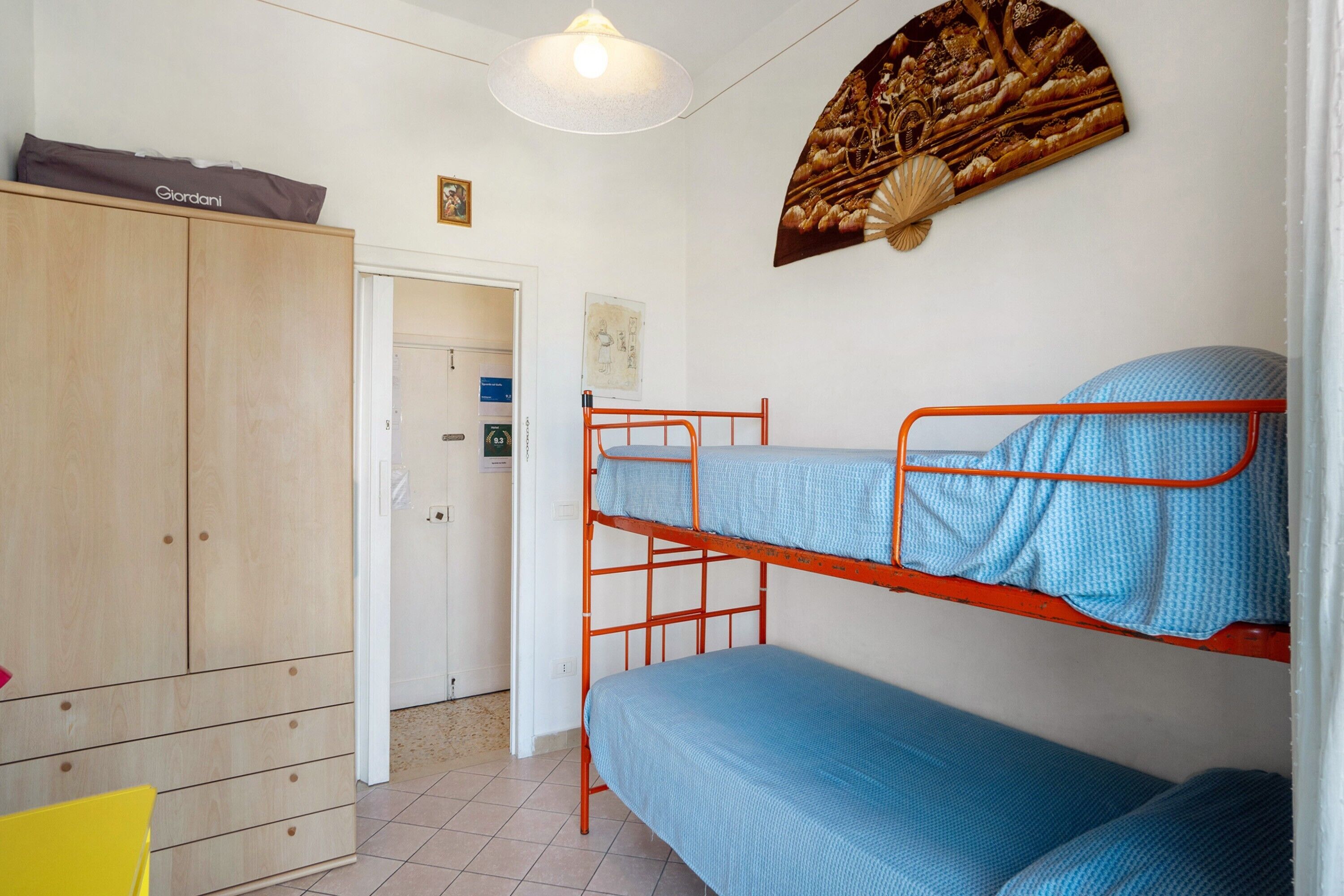 Une chambre avec un lit superposé, une armoire et une porte donnant sur une autre pièce.