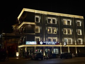 A multi-story building with illuminated signage for a hotel and restaurant. - Royal Palm Inn (Faizabad)