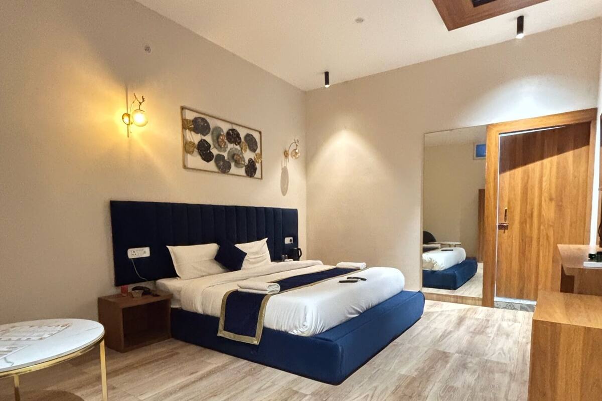 A modern bedroom with a bed, bedside tables, a round table, and a mirror.