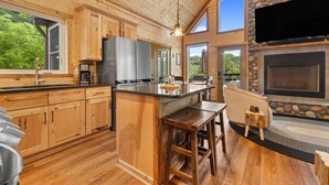 Une cuisine spacieuse avec des meubles en bois, un grand îlot central et une cheminée en pierre.