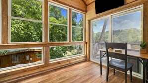 Une pièce dotée de grandes fenêtres, de planchers en bois et d’une table avec une chaise.