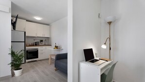 A modern kitchen with white cabinets, a built-in oven, and a dining area with a blue sofa. - Vacation Home 'El Rinconcito De Niña' with Sea View, Private Terrace and Wi-Fi (Tijoco Bajo)