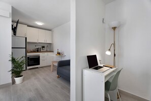 A modern kitchen with white cabinets, a built-in oven, and a dining area with a blue sofa.