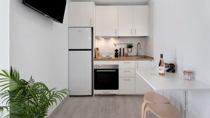 A modern kitchen with white cabinets, a built-in oven, a refrigerator, and a flat-screen TV mounted on the wall. - Vacation Home 'El Rinconcito De Niña' with Sea View, Private Terrace and Wi-Fi (Tijoco Bajo)