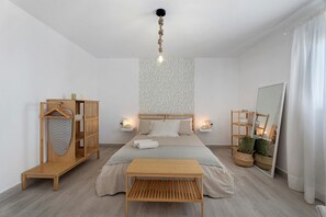 A bedroom with a bed, bedside tables, a hanging light fixture, a wardrobe, a mirror, and a window with curtains. - Vacation Home 'El Rinconcito De Niña' with Sea View, Private Terrace and Wi-Fi (Tijoco Bajo)