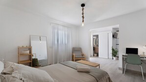 A minimalist bedroom with a bed, a desk, a chair, a mirror, and a hanging light fixture. - Vacation Home 'El Rinconcito De Niña' with Sea View, Private Terrace and Wi-Fi (Tijoco Bajo)