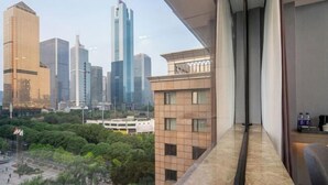 Habitación de hotel en un edificio alto con vista a la ciudad, ventanas amplias y decoración moderna.