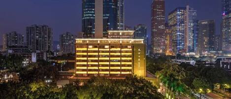A modern hotel with a multi-story structure, surrounded by a dense urban skyline at night.