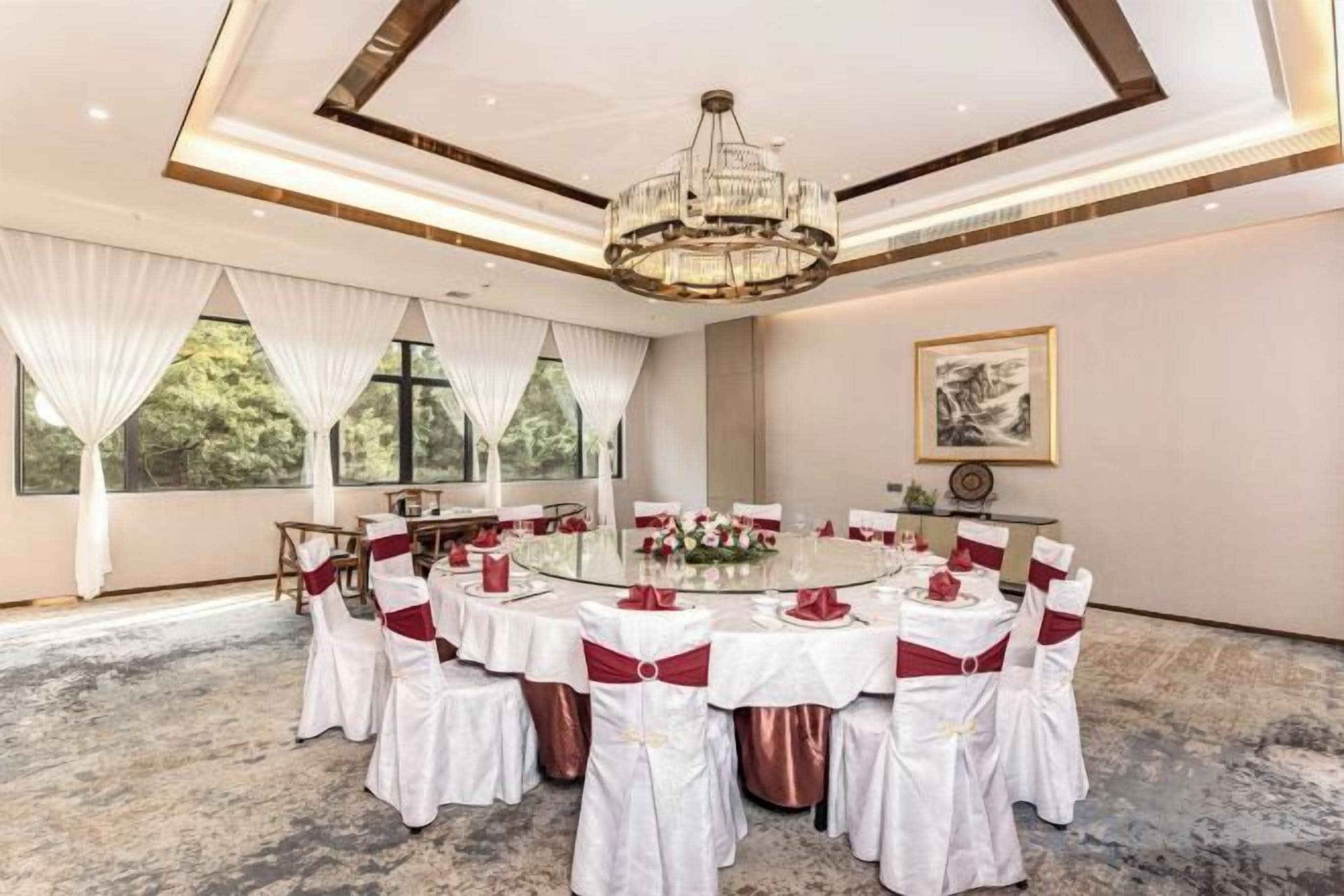 Un salón de conferencias con una mesa redonda, sillas blancas y rojas, y una lámpara de araña.