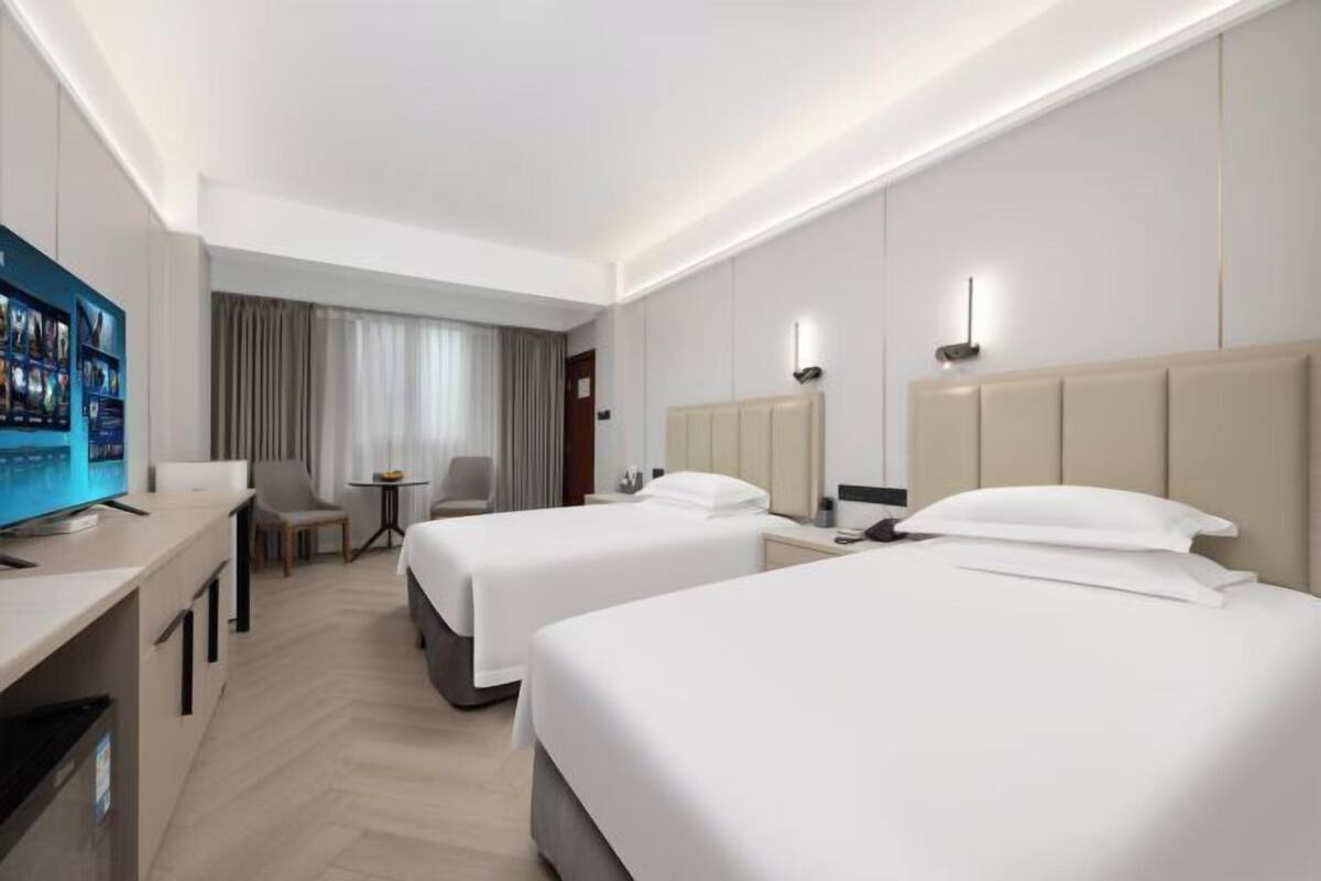 Une chambre d’hôtel avec deux lits, une télévision, un bureau et une petite table.