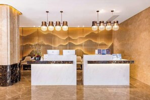 A reception area with marble counters, a modern light fixture, and a decorative wall.
