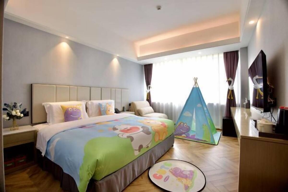 Une chambre d’hôtel comprenant un lit, un bureau, une chaise, une fenêtre avec des rideaux et une structure ressemblant à une tente.