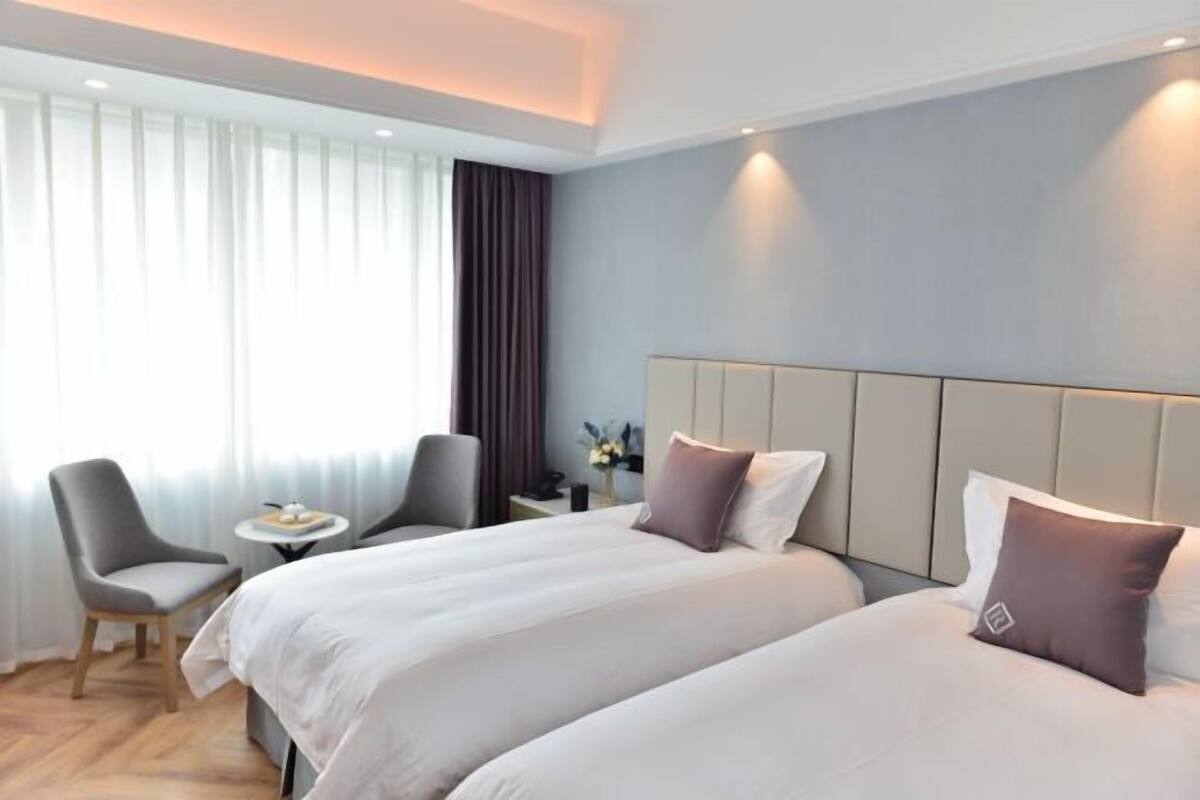 Une chambre d’hôtel avec deux lits, une petite table, une chaise et une table de chevet.