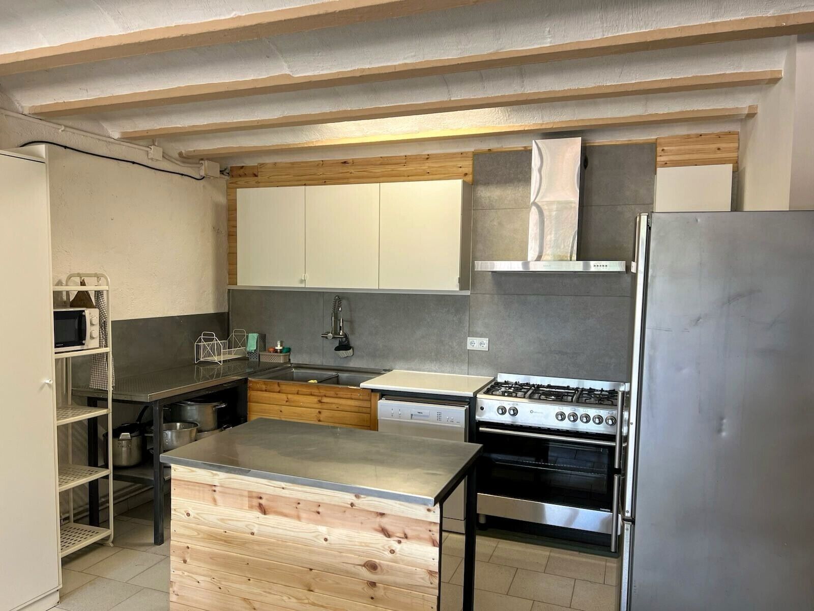 Eine moderne Küche mit einer zentralen Kochinsel, Edelstahlgeräten und Holzschränken.