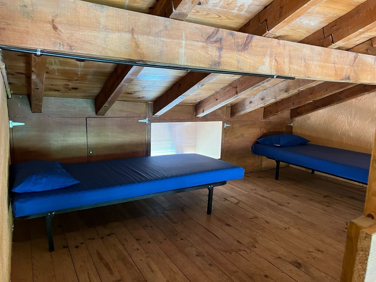 Un pequeño dormitorio en ático con dos literas, vigas de madera y techo inclinado.