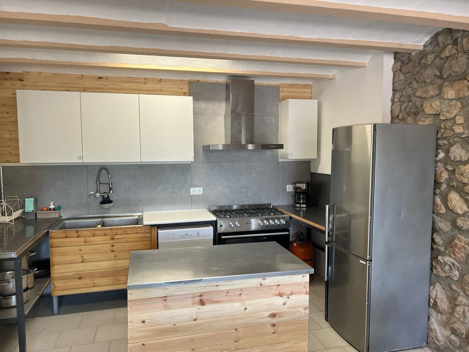 A modern kitchen with a built-in stove, stainless steel refrigerator, and wooden cabinetry.