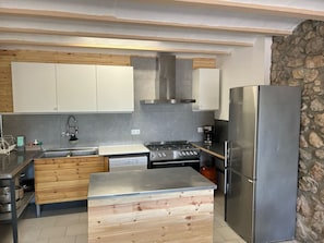 Een moderne keuken met een ingebouwde kookplaat, een koelkast van roestvrij staal en houten keukenkastjes.