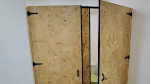 A room with a wooden wardrobe, a toilet, and a white wall. - Cal Caló – Colònies Cadí is a mountain farmhouse for peaceful groups in Cortariu, La Cerdanya. (Bellver De Cerdanya)