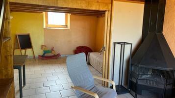Une pièce avec un plafond en bois, une cheminée, un lit, un cheval à bascule et une chaise.