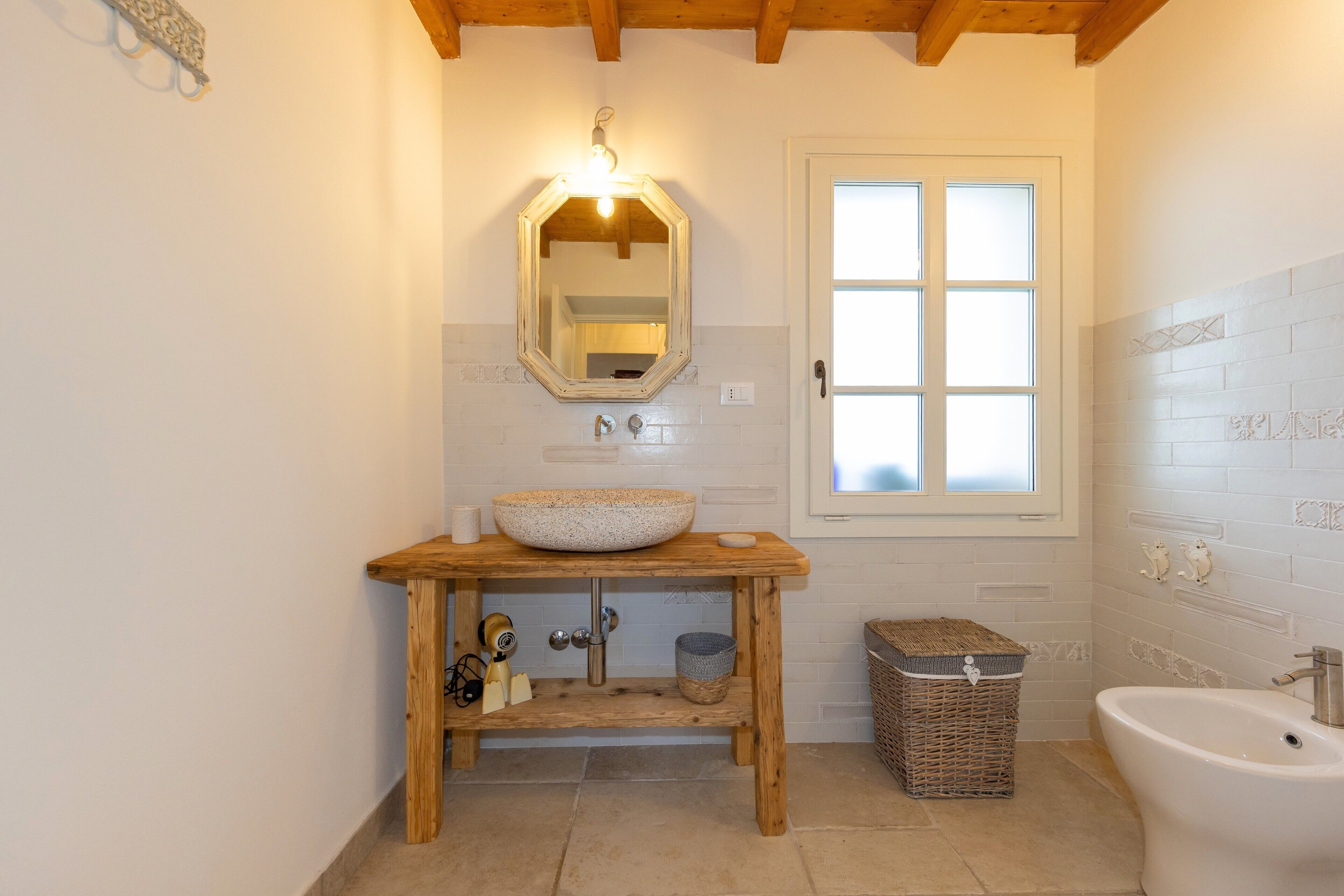 A bathroom with a wooden vanity, a large mirror, a sink, a bathtub, and a window.