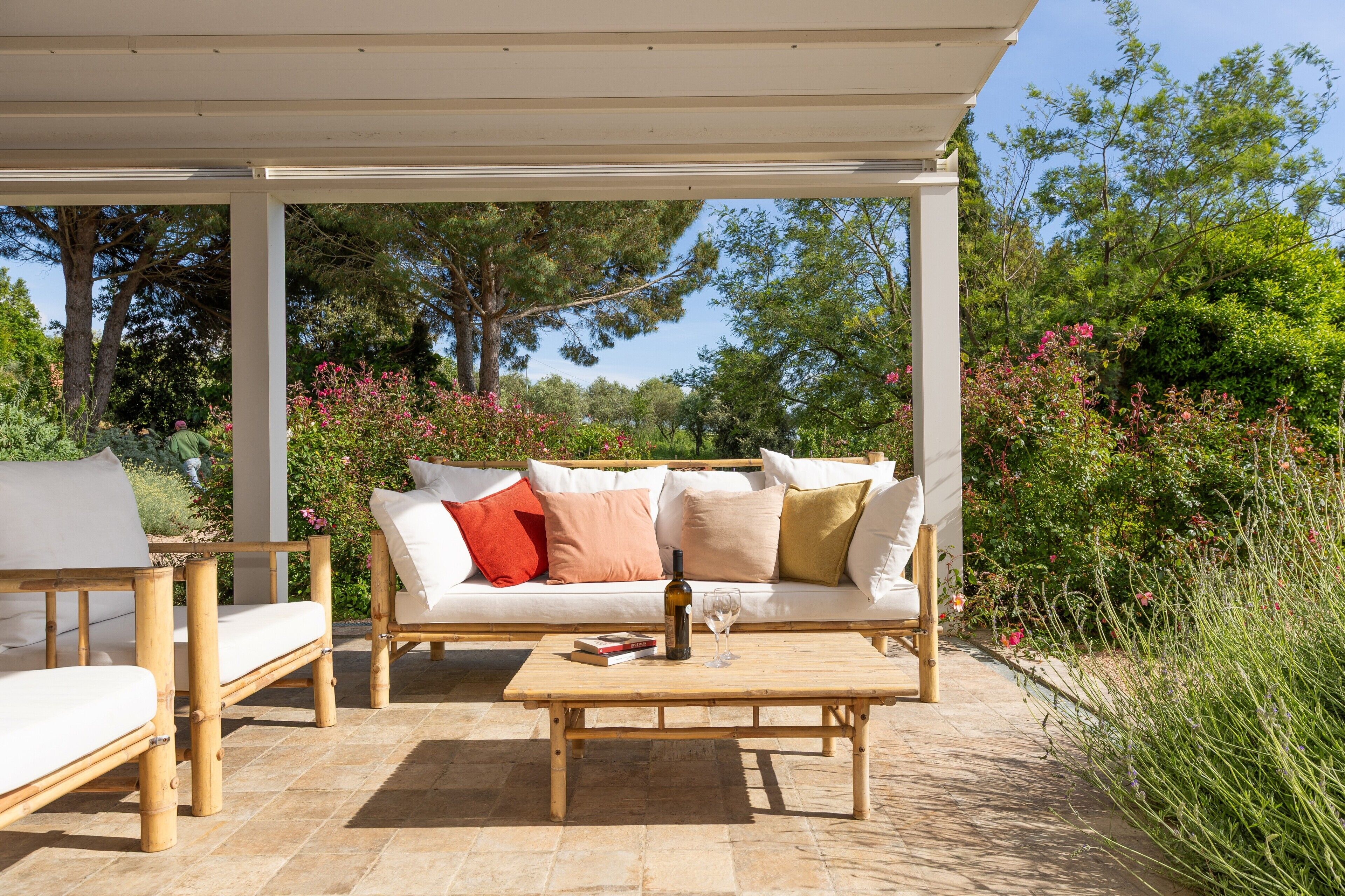 Ein Sitzbereich im Freien mit einem Holztisch, einer Couch mit Kissen und einer Pergola.