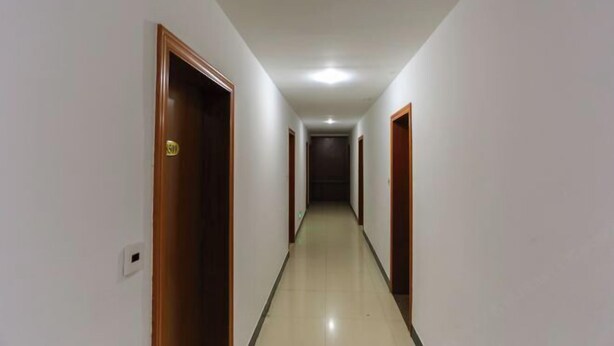 A long, narrow hallway with wooden doors on both sides, leading to a dark room at the end. - Jinxiu Hotel (Tonglu)