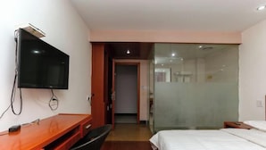 A hotel room with a wooden desk, a flat-screen TV, a bed, and a glass partition wall. - Jinxiu Hotel (Tonglu)