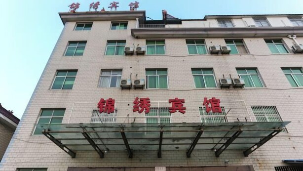 A building with multiple floors, featuring a prominent sign with red characters. - Jinxiu Hotel (Tonglu)
