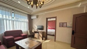 A hotel room with a sofa, a coffee table, a TV, a desk, and a bed. - Donggang Yuyun Hotel (Donggang)