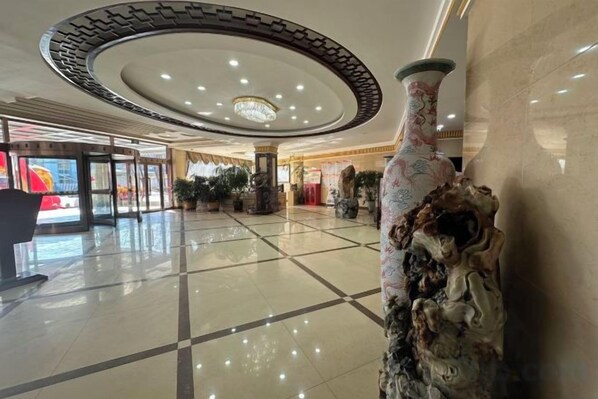 Eine Hotelhalle mit einer großen, aufwendigen Vase, einem Chandelier und einem gefliesten Boden.