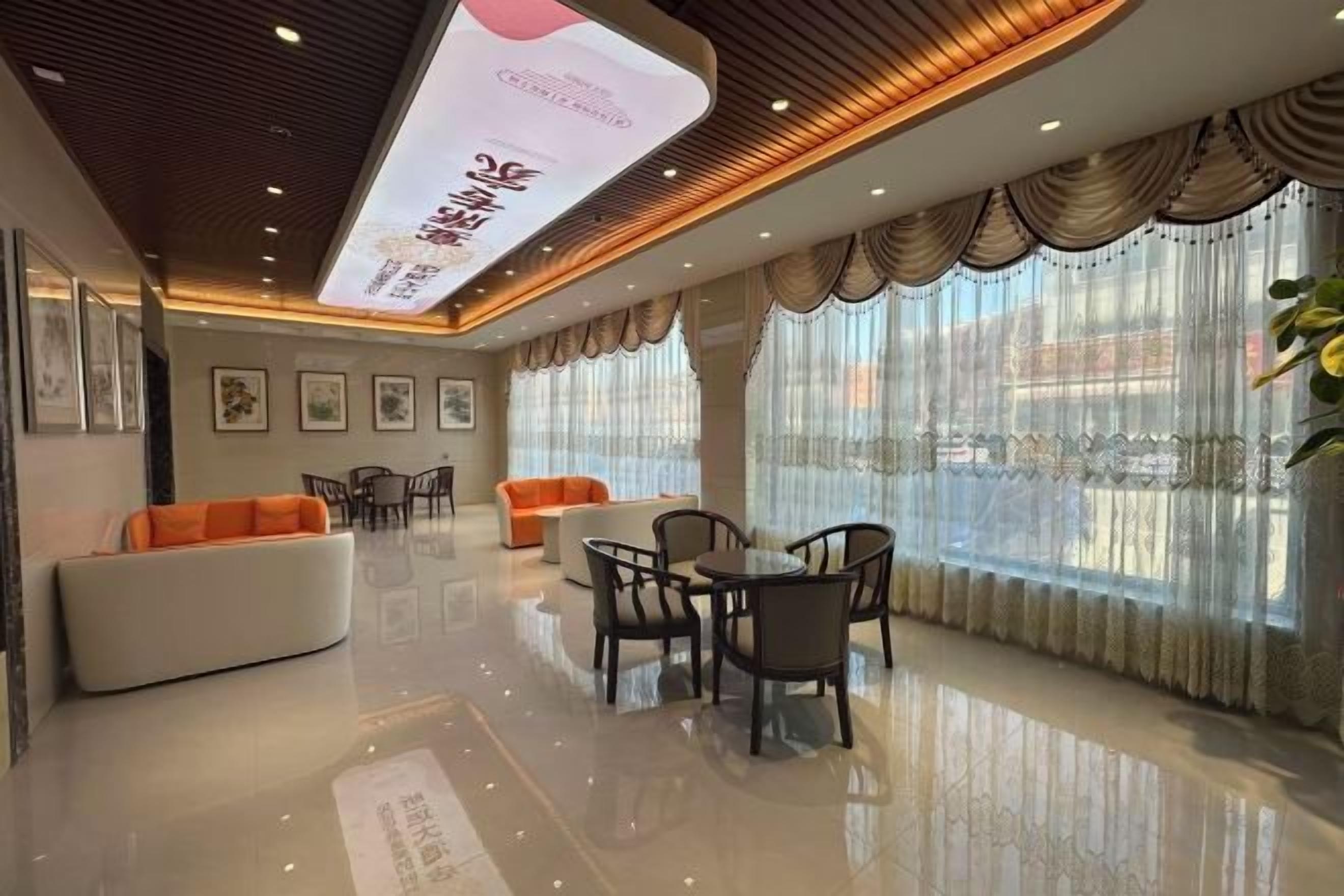 A hotel lobby with a reception desk, seating area, and large windows.