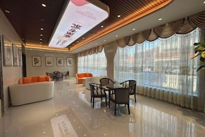 Un vestíbulo de hotel con mostrador de recepción, zona de estar y amplias ventanas.
