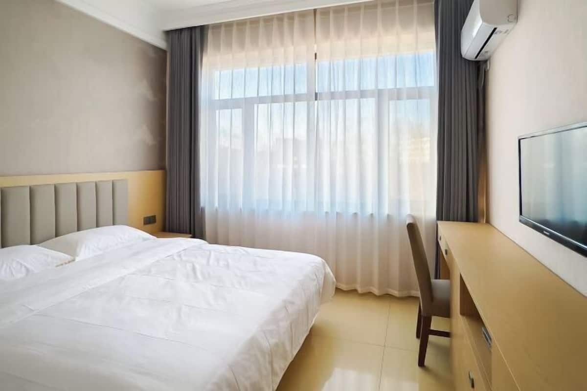A hotel room with a bed, a desk, and a TV.