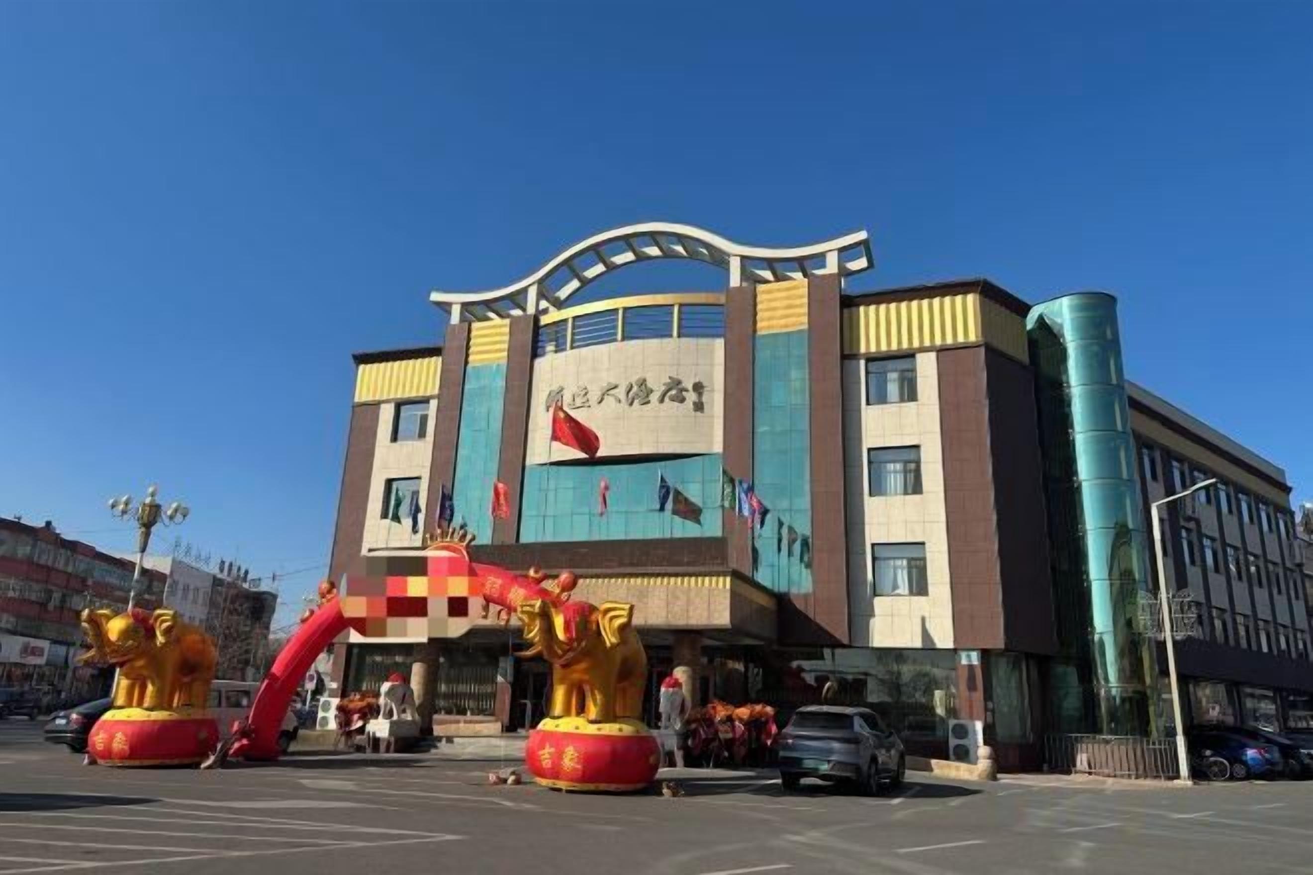 A multi-story building with a prominent entrance, large windows, and a clear sky.