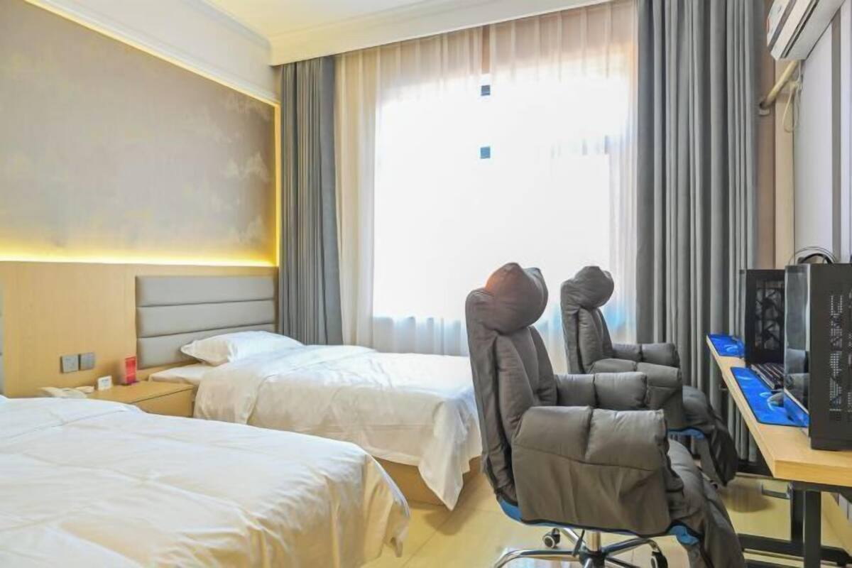 A hotel room with two beds, a desk with a computer, and a chair.