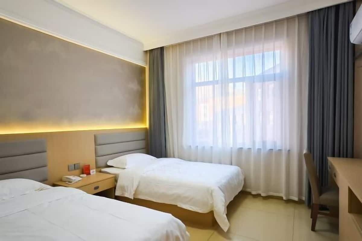 A hotel room with two beds, a desk, and a chair.